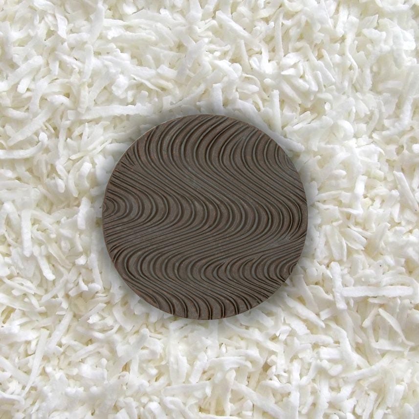 One piece of sugar-free Goalz chocolate with wavy designs lying on a bed of coconut shreds