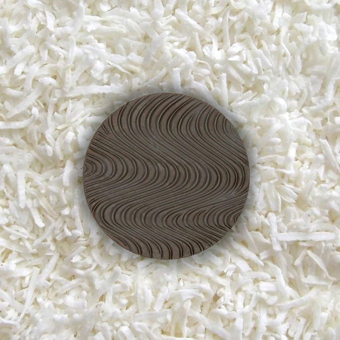 One piece of sugar-free Goalz chocolate with wavy designs lying on a bed of coconut shreds