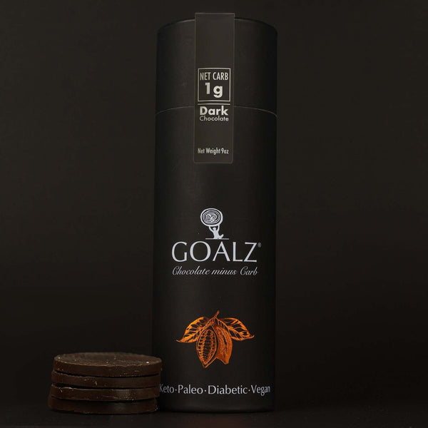 Original Allulose sweetened Goalz dark Keto Chocolate standing on a dark background and next to circular sugar-free chocolate bars stacked.